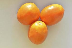 Three yellow ripe tomatoes on a white background photo