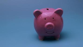 Finance saving concept. Money throwing in the piggy bank euro coins. Piggy Bank pig throwing a trifle against a blue background. video