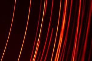 Bright red diagonal vertical lines of rays on a dark background. Abstract photo