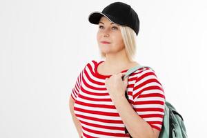 middle-aged woman in a black cap and with a backpack looks away isolated on white background photo