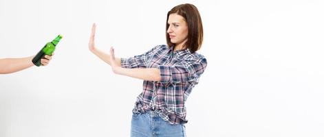 A concept of alcoholism. A young woman saying no sign to alcoholic beverage bottles. photo