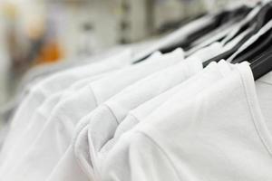 Some used clothes hanging on a rack in a flea market. Background of dress. Selective focus. photo