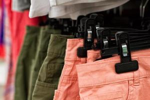 Some used clothes hanging on a rack in a flea market. Background of dress. Selective focus. photo