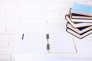 Open notebook with copy space and books on workplace. Top view and selective focus photo