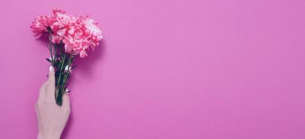 Summer flowers composition with girl hand isolated on pink background. Mother and women day. Valentine holidays concept. Top view and copy space. Banner and mock up. Flower season photo