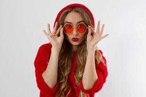 Happy, shock, excited woman face closeup. Girl in bright red hoodie autumn clothes red sunglasses isolated. white background, copy space. Beautiful female surprised, cheerful. model Fun time photo