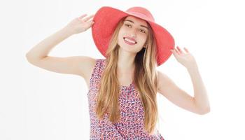 Portrait of a smiling attractive woman in summer dress and hat posing while standing and looking at camera isolated over white background. photo