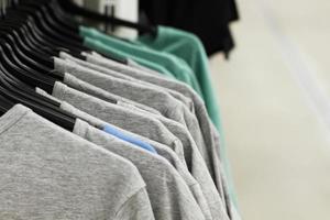 Some used clothes hanging on a rack in a flea market. Background of dress. Selective focus. photo