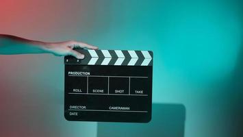 Hand holds empty film making clapperboard on color background in studio photo