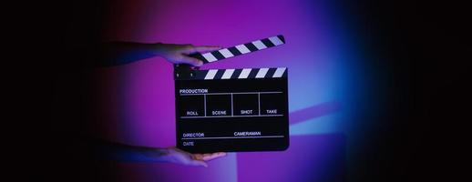 Hand holds empty film making clapperboard on color background in studio photo