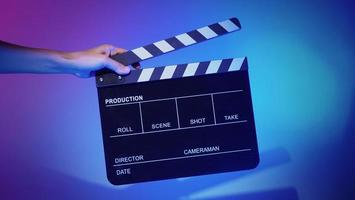 Hand holds empty film making clapperboard on color background in studio photo