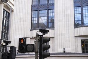 Pedestrian red traffic light with speed cameras on pole against building photo