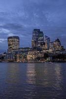 View of illuminated modern financial district skyscrapers from river thames photo