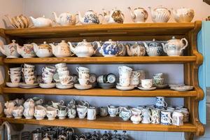 Assortment of hand painted ceramic floral pattern tea sets on shelves photo