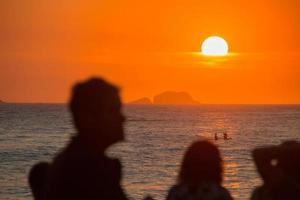 silhouette of people watching the sunset at arpoador beach in rio de janeiro. photo