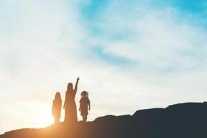 silueta de madre con su hija de pie y puesta de sol foto