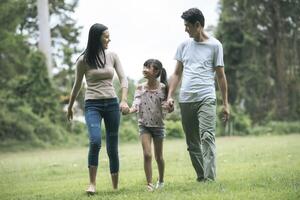 Happy parents and their daughter walking in the park, Happy family concept. photo