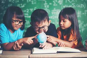 kid observing or studying educational globe model in the classroom. photo