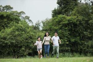 Happy family is having fun Mother, father and daughter are running in park. photo