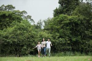 la familia feliz se divierte madre, padre e hija corren en el parque. foto