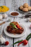 pollo frito, tenedor y salsa picante en una taza blanca con especias en un suelo de madera blanca foto