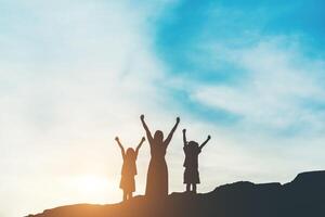 silueta de madre con su hija de pie y puesta de sol foto