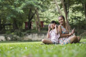 Mother and daughter reading a fairytale to her daughter listen sound with headphone in the park photo