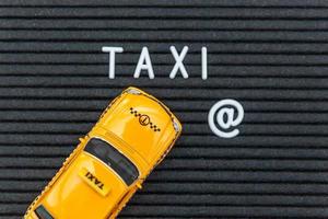 simplemente diseñe un modelo de taxi de coche de juguete amarillo con letras de taxi de inscripción palabra sobre fondo negro. símbolo de automóvil y transporte. concepto de idea de servicio urbano de entrega de tráfico de la ciudad. copie el espacio foto