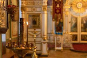 Iglesia Ortodoxa. cristiandad. decoración interior festiva con velas encendidas e icono en la iglesia ortodoxa tradicional en vísperas de pascua o navidad. religión fe orar símbolo. foto