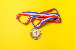 Simply flat lay design winner or champion gold trophy medal isolated on yellow colorful background. Victory first place of competition. Winning or success concept. Top view copy space. photo