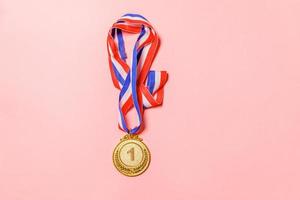 Simply flat lay design winner or champion gold trophy medal isolated on pink colorful background. Victory first place of competition. Winning or success concept. Top view copy space. photo