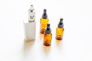 Vaping device e-cigarette electronic cigarette and liquid bottles isolated on white background. Vape device for alternative smoking. Vaping shop concept. Gadget for vaper. Vaping accessories. photo