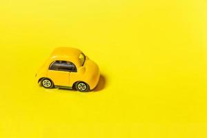 simplemente diseñe un coche de juguete retro vintage amarillo aislado sobre fondo amarillo. símbolo de automóvil y transporte. espacio de copia del concepto de entrega de tráfico de la ciudad foto