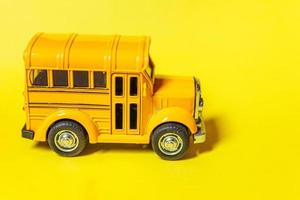 Simply design yellow classic toy car school bus isolated on yellow colorful background. Safety daily transport for kids. Back to school concept. Education symbol, copy space photo