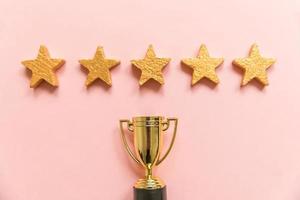 Simply flat lay design winner or champion gold trophy cup and 5 stars rating isolated on pink pastel background. Victory first place of competition. Winning or success concept. Top view, copy space photo