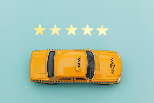Yellow toy car Taxi Cab and 5 stars rating isolated on blue background. Smartphone application of taxi service for online searching calling and booking cab concept. Taxi symbol. Copy space. photo