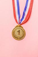 Simply flat lay design winner or champion gold trophy medal isolated on pink colorful background. Victory first place of competition. Winning or success concept. Top view copy space. photo