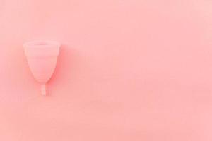 copa menstrual de diseño simplemente minimalista aislada sobre fondo rosa pastel. mujer alternativa moderna eco higiene ginecológica en el período de la menstruación. recipiente para sangre. vista superior plana, espacio de copia foto