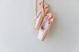 New pastel beige ballet shoes with satin ribbon isolated on white background. Ballerina classical pointe shoes for dance training. Ballet school concept, Copy space photo