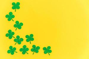 St Patricks Day background. Simply minimal design with green shamrock. Clover leaves isolated on yellow background. Symbol of Ireland. Lucky fortune wish concept. Flat lay top view layout copy space. photo