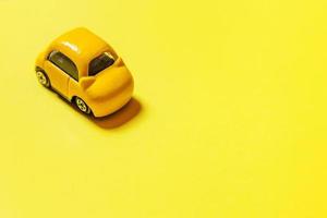 simplemente diseñe un coche de juguete retro vintage amarillo aislado sobre fondo amarillo. símbolo de automóvil y transporte. espacio de copia del concepto de entrega de tráfico de la ciudad foto