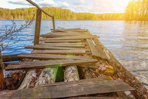 Forest lake or river on summer day and old rustic wooden dock or pier photo