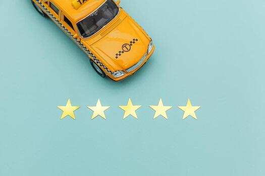 taxi de coche de juguete amarillo y calificación de 5 estrellas aislado sobre fondo azul. aplicación de teléfono inteligente del servicio de taxi para buscar en línea llamadas y reservar el concepto de taxi. símbolo de taxi. copie el espacio foto