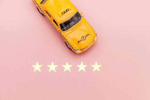 Yellow toy car Taxi Cab and 5 stars rating isolated on pink background. Smartphone application of taxi service for online searching calling and booking cab concept. Taxi symbol. Copy space. photo