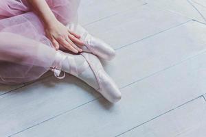 Ballerina hands puts pointe shoes on leg in dance class photo