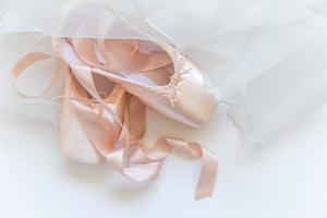 nuevos zapatos de ballet beige pastel con cinta satinada y falda tutut aislados en fondo blanco. Bailarina de punta clásica para entrenamiento de baile. concepto de escuela de ballet. vista superior plana, espacio de copia foto