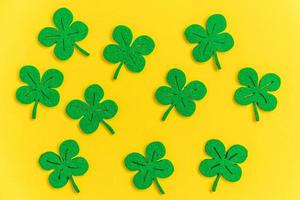 St Patricks Day background. Simply minimal design with green shamrock. Clover leaves isolated on yellow background. Symbol of Ireland. Lucky fortune wish concept. Flat lay top view layout copy space. photo