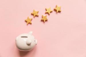 Simply minimal design piggy bank 5 gold stars isolated on pink background. Bank rating. Saving investment budget business retirement financial money banking concept. Flat lay top view copy space. photo