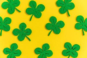 St Patricks Day background. Simply minimal design with green shamrock. Clover leaves isolated on yellow background. Symbol of Ireland. Lucky fortune wish concept. Flat lay top view layout copy space. photo