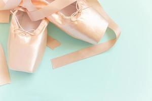 nuevos zapatos de ballet beige pastel con cinta satinada aislados en fondo azul. Bailarina de punta clásica para entrenamiento de baile. concepto de escuela de ballet. vista superior plana, espacio de copia foto